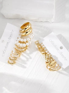 Detail of multi-pair vintage geometric C-shaped gold alloy and pearl earring sets