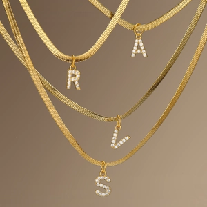 Detailed view of gold snake chain necklaces featuring crystal-set A, R, V, and S pendants