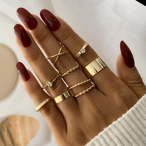 Close-up of golden geometric stackable rings set featuring twisted and minimalist designs