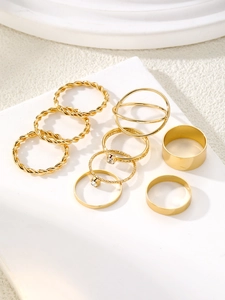 Detailed close-up of 9-piece golden twisted and geometric minimalist ring set on stone