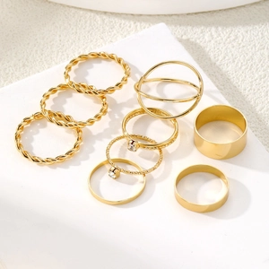 9-piece gold twist rings set with square crystals and minimalist bands on white background