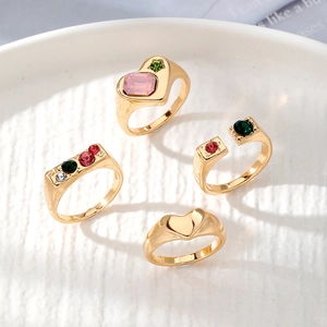 Set de cuatro anillos dorados con piedras rosas de corazón y circonitas de colores