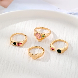 Set de cuatro anillos dorados con circones de colores en forma de corazón y gemas