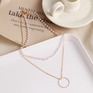 Elegante Lagen-Perlenkette mit Goldkette und Rundanhänger auf einem weißen Tablett