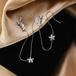 Elegant silver tassel earrings with zircon flower pendants on silk and velvet background