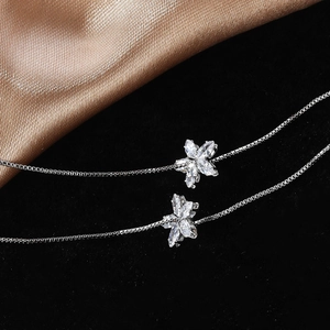 Detailed macro view of silver flower earrings with marquise zircon and box chain