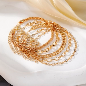 Detail von mehrlagigen goldenen Boho-Armbändern mit Kettenmustern und Herz-Anhängern
