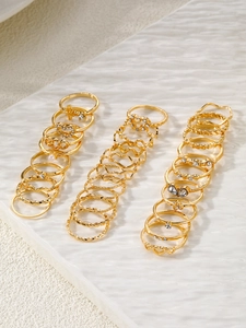 Detailed set of 30 golden rings with pearls and rhinestones on white display