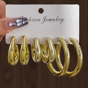 Detailed set of three polished gold-tone hoop and teardrop earrings on fashion card