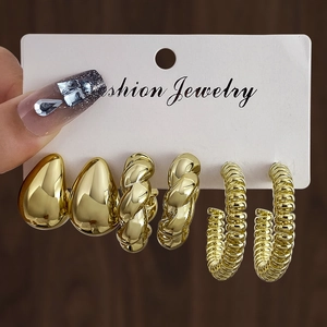 Detail view of a 3-pair set of chunky gold hoop earrings with twisted and textured patterns