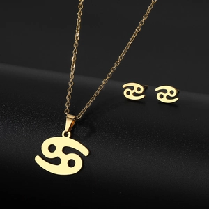 Gold Cancer zodiac sign necklace and stud earrings set on a dark textured background