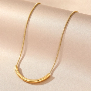 Minimalist gold smile curved bar necklace on silk background for elegant women's style