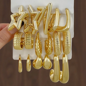 Close-up of golden mixed earring set featuring star shapes and braided hoops on a card