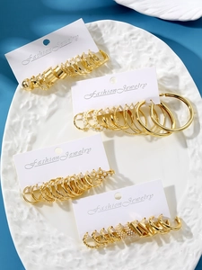 Dettaglio di set orecchini a cerchio dorati geometrici con perle su vassoio elegante