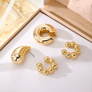 Poliertes Gold-Ohrring- und Ear-Cuff-Set auf weißem Schmuckdisplay aus Leder
