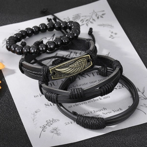 Dettaglio di 4 bracciali da uomo con perline nere, cuoio intrecciato e ciondolo piuma