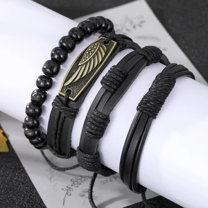 Dettaglio del set di quattro bracciali in pelle nera retrò con piuma e perline