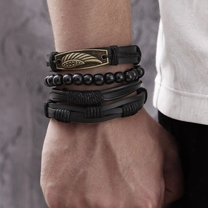 Dettaglio di bracciali multistrato in pelle nera vintage con ciondolo a piuma di bronzo