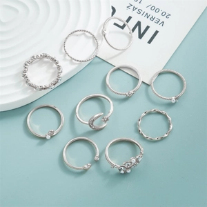 Set of 9 silver alloy rings featuring moon star motifs and faux pearls on light blue background