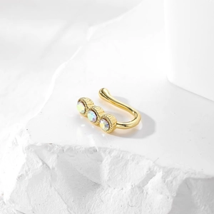Golden U-shaped non-piercing nose cuff with three iridescent rhinestones on white stone