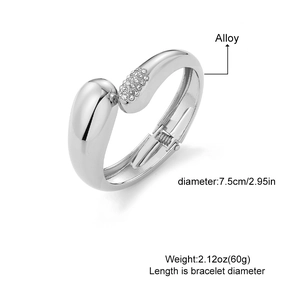 Wide silver geometric wave bangle with teardrop rhinestone accents and hinged closure