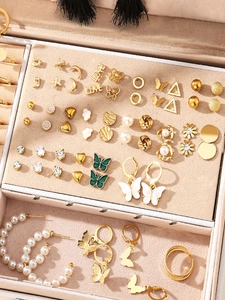Detailopname van gouden sieradenset met imitatieparels, strass en vlindermotieven