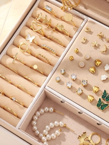 Gedetailleerd bovenaanzicht van gouden sieradenset met parels en emaille in beige doos
