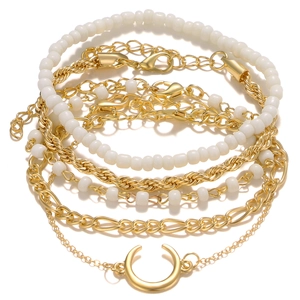 Détail d'un ensemble de bracelets dorés avec perles blanches et pendentif croissant