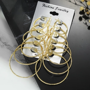 Detail view of 6 gold hoop earring sets with geometric texture on a marble display