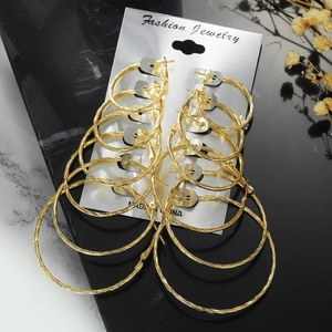 Set of 6 pairs golden hoop earrings with twisted texture on marble background