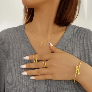 Conjunto de joyas doradas geométricas modernas con collar, brazalete y anillos en modelo