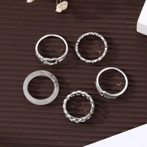Five-piece silver finish ring set with heart and rope designs on dark texture