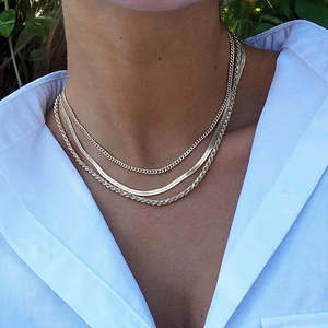 Ensemble de trois colliers dorés avec maille gourmette, serpent et torsadée porté par mannequin