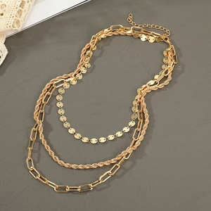 Détail de colliers dorés multicouches avec maillons torsadés et fermoir mousqueton