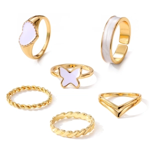 Vista detallada de seis anillos dorados con diseños de corazón y mariposa en esmalte