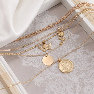 Multilayer gold necklace set with angel, rose, and coin pendants on silk background