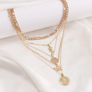Layered gold necklace featuring angel portrait and rose coin pendants on silk background