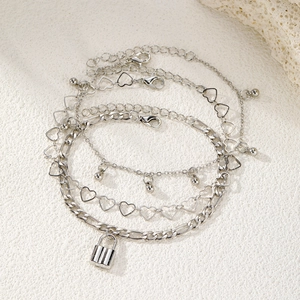 Detail of silver layered anklet set with heart links, beads and a small lock charm