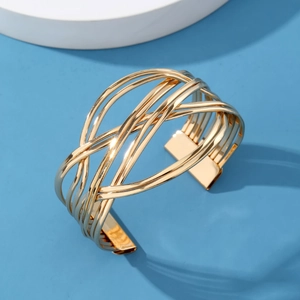 Gold hollow geometric wrap cuff bracelet with interlaced lines on a blue background