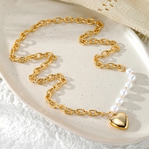 Detalle del colgante de corazón dorado y perlas de imitación en collar de cadena