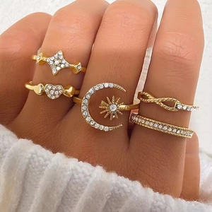 Detailed close-up of a 5-piece gold ring set featuring star, moon, and heart designs with crystals