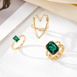 Gold-tone 3-piece ring set featuring emerald green gemstones and hollow heart design