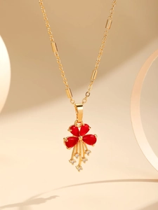 Detail of gold-plated tassel necklace with red gemstone petals and sparkling zircon accents