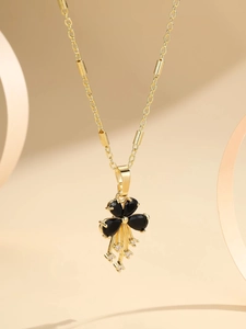 Detail of gold-plated necklace with black stone flower and zircon tassel pendant