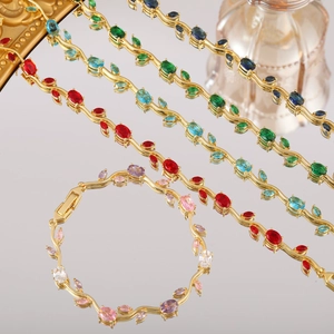 Vista ravvicinata di collana e bracciale a vite dorata con gemme ovali multicolore