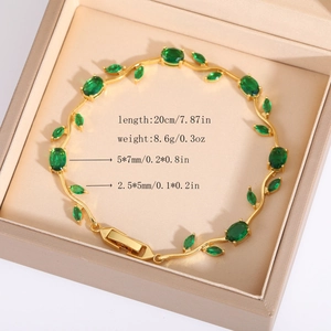Dettaglio del bracciale a foglia dorata con pietre verdi su espositore beige