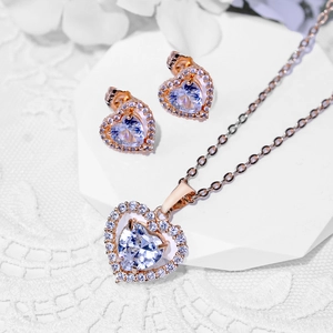Elegant rose gold heart jewelry set with necklace and earrings on white pedestal