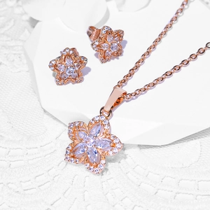 Rose gold flower jewelry set with necklace and earrings on white lace background