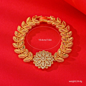 Detail of gold floral bracelet with white zircon stones on red textured background