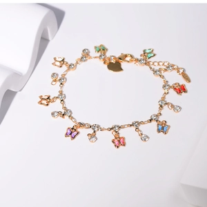 Détail d'un bracelet doré avec des breloques papillons colorés et des zircons brillants